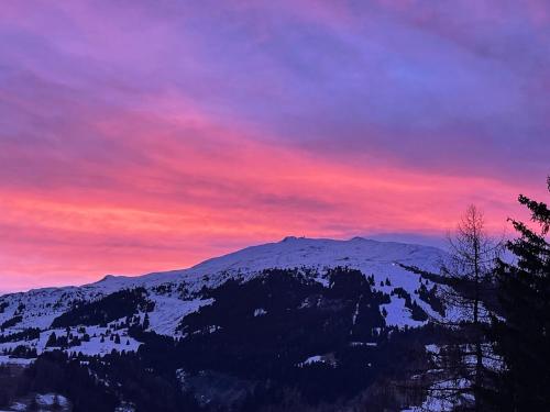 a sunset over a mountain with snow on it at Savognin Rundigna in Savognin