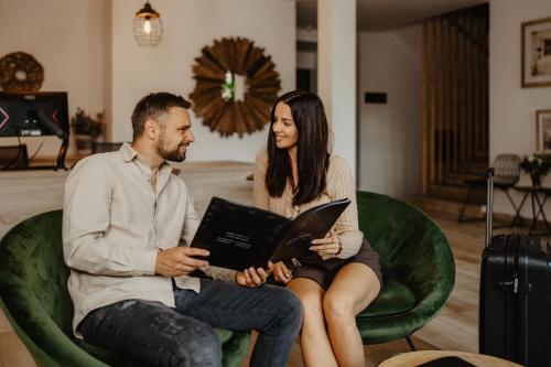 a man and woman sitting in a green chair with a laptop at Hotel Frýdl in Prague