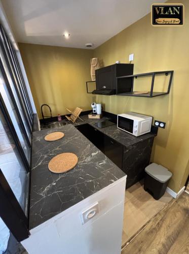 a kitchen with a black counter top and a microwave at A l'angle du vieux marché in Niort