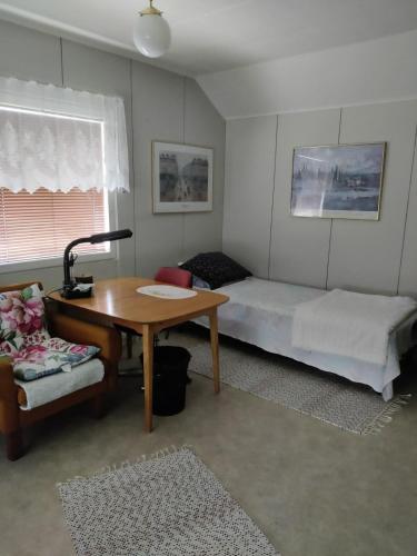 a room with a desk and a bed and a table at Puskan Mummola in Pello