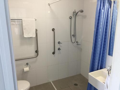 a bathroom with a shower with a toilet and a blue shower curtain at Aquarius Apartments Mollymook in Mollymook