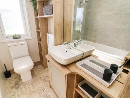 a bathroom with a sink and a toilet and a tub at Curlew Lodge in Carnforth