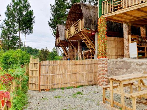 a wooden house with a fence and a wooden bench at Ciwidey Jungle Camp & Cabin in Gambung