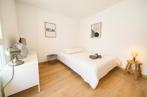 里昂Functional and well located studio close to metro and shops的一间带床和风扇的白色卧室