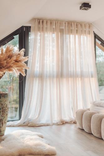 a white curtain in a room with a window at W szczerym lesie - Domek z sauną i jacuzzi w lesie nad Jeziorem Mucharskim in Dąbrówka