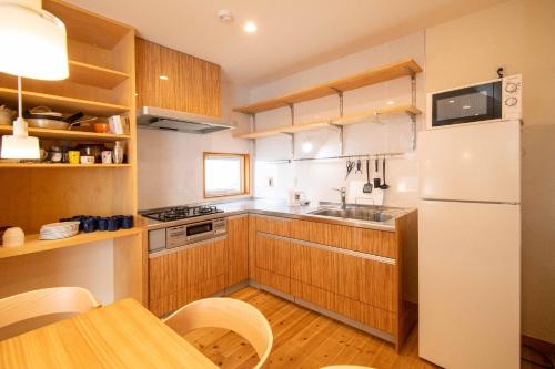 eine Küche mit Holzschränken und einem weißen Kühlschrank in der Unterkunft Muku House Urayasu in Tokio
