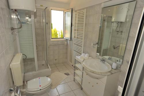 a white bathroom with a sink and a toilet at Seaside apartments with a swimming pool Sutivan, Brac - 16846 in Sutivan