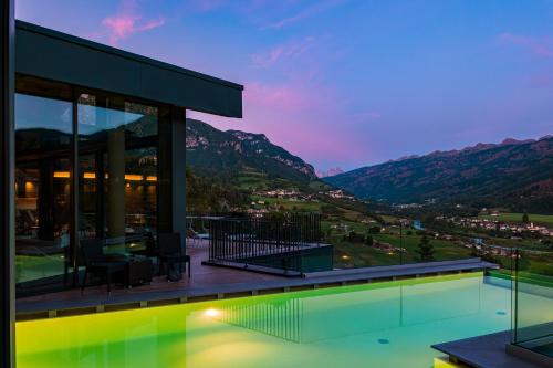 a house with a swimming pool at dusk at La Roccia Wellness Hotel in Cavalese