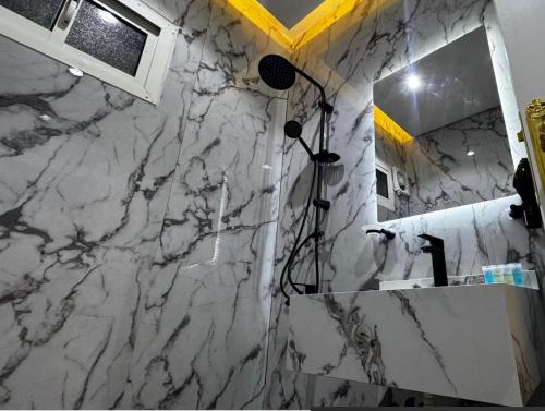a bathroom with a marble wall with a shower and a mirror at غرفة بجاكوزي مع صالة 1 من أرام ريزدنس by ARAM Residence in Aţ Ţuwayr