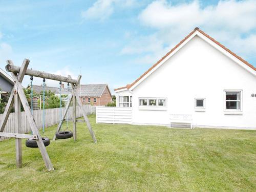 a yard with two swings in front of a house at 10 person holiday home in Thisted-By Traum in Klitmøller