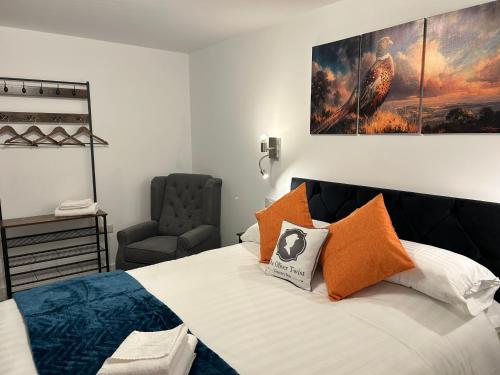 a bedroom with a bed with a chair and a painting on the wall at Oliver Twist Country Inn in Wisbech