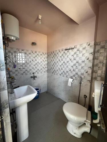 a bathroom with a white toilet and a sink at GRETZbnb in Shillong