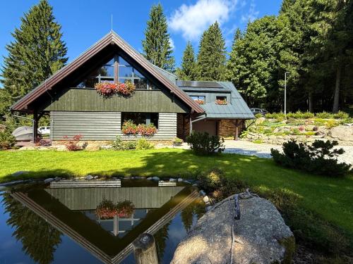 a house with a pond in front of it at apartmány V Lese in Bedřichov