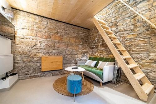 una stanza con un muro di pietra, un divano e delle scale di Le petit Victor Hugo - studio Bellecour a Lione