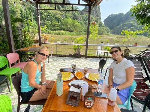 two women sitting at a table on a patio at Tam Coc My Tho Homestay in Vũ Lâm