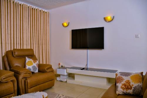 a living room with a tv and a couch and a chair at Genesis Grove BnB Syokimau in Syokimau