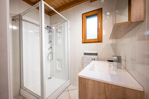 a white bathroom with a shower and a sink at Chalet La Petite Maison in Saint-Marcel