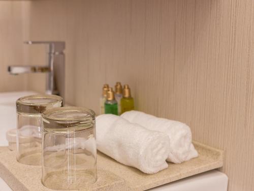a bathroom counter with towels and two glass jars at Marfa Aliah for service apartments شقق مرفأ عالية للشقق المخدومة in Khamis Mushayt