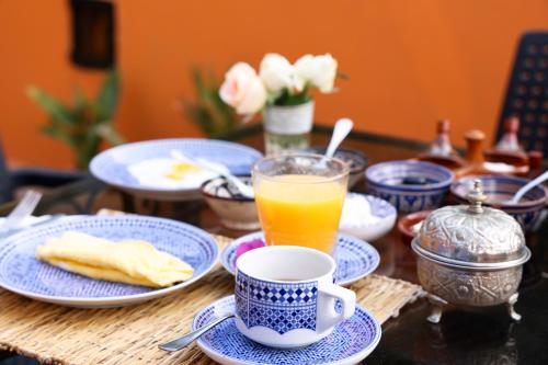 a table with blue and white plates and a cup of orange juice at Dar Rass El Maa in Chefchaouene