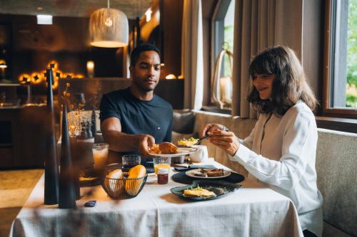 Um homem e uma mulher sentados à mesa a comer. em Boutique Hotel Mandarfnerhof em Sankt Leonhard im Pitztal