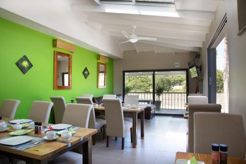 een eetkamer met groene muren en tafels en stoelen bij Pinto City Motel East London in East London