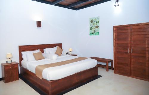ein Schlafzimmer mit einem großen Bett und Holzschränken in der Unterkunft Ibbankatuwa Lake Resort in Dambulla