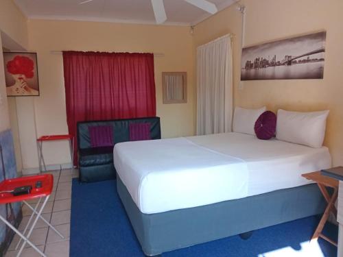 a bedroom with a large white bed and a chair at Yana STAYS in Polokwane