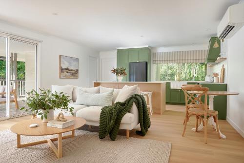 a living room with a couch and a kitchen at Oak Ridge Cottage in Maleny