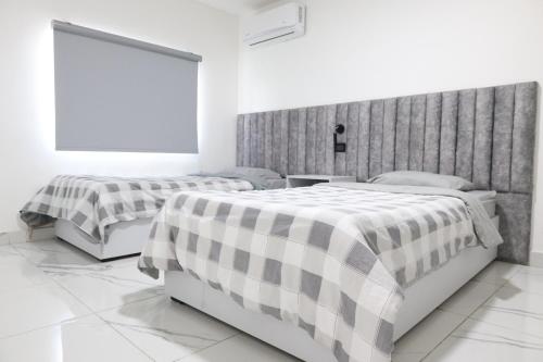 two beds in a white room with a window at ريلاكس للاجنحة الفندقية in Amman
