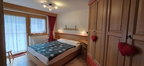 a bedroom with a bed and a desk and a window at Casa Aloch da Aldo Gianni in Pozza di Fassa