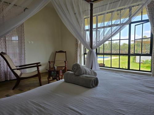 a bedroom with a bed and a large window at Kipepeo Villa in Naivasha