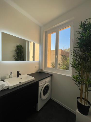 a bathroom with a sink and a washing machine at Élégance & confort - aux portes de Paris in Aulnay-sous-Bois