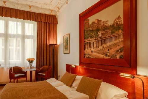 a hotel room with a bed and a painting on the wall at Hotel Golden Lamb in Karlovy Vary