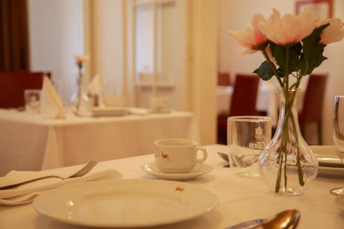 una mesa con un jarrón de flores rosas y una taza en Hotel Golden Lamb, en Karlovy Vary