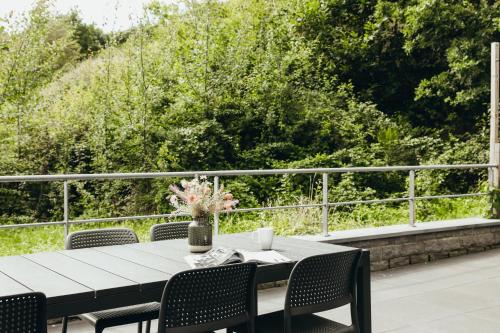 a table with chairs and a vase of flowers on a patio at Au pied du pré, Appartement 6P in Verviers