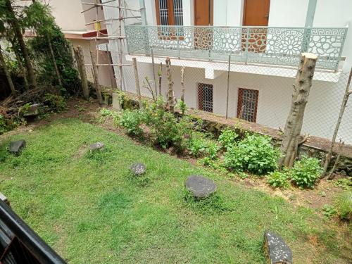 a garden with rocks in the grass next to a building at Kodai ARYASREE in Kodaikānāl