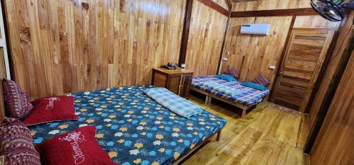a room with two beds in a room with wooden walls at Trạm Thẩm Lé in Văn Chấn