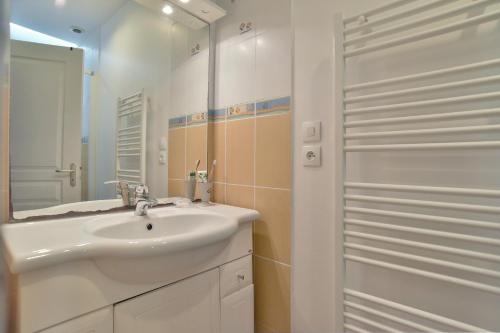 a white bathroom with a sink and a mirror at Appartement Terre - 400m de la Plage in Saint-Lunaire