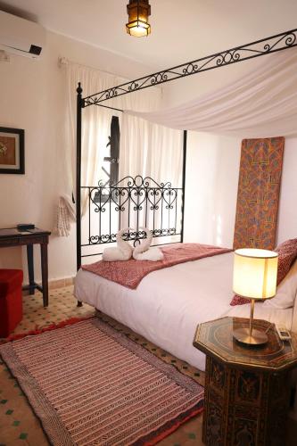 a bedroom with a canopy bed with a lamp and a table at Dar Rass El Maa in Chefchaouen