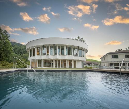 a large house with a swimming pool in front of it at Resort Hof Weissbad in Weissbad