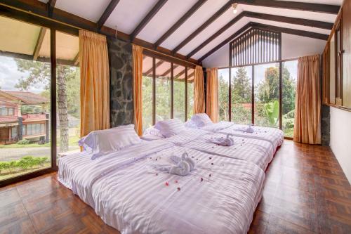 a large bed in a room with large windows at Villa Pinokio W BBQ & Backyard in Bandung
