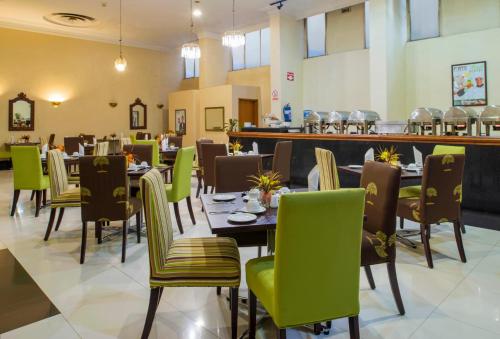 哈拉雷的住宿－新大使酒店，用餐室配有桌子和绿色椅子