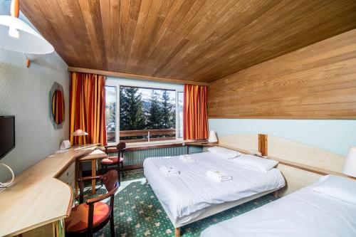 a room with two beds and a desk and a window at Villages Clubs du Soleil - VARS in Vars