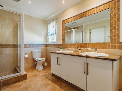 a bathroom with two sinks and a shower and a toilet at Trafford Cottage on Kingswood Golf Estate in George