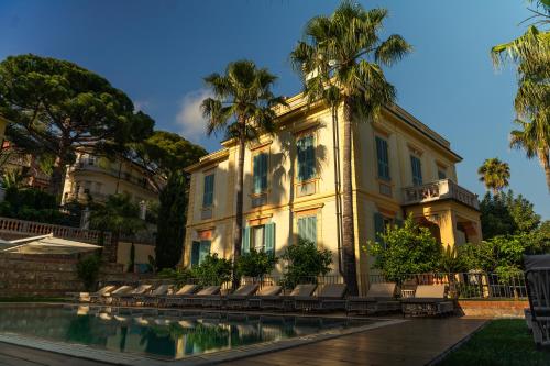 un edificio con palmeras frente a una piscina en Alaxia Exclusive Apartments, en Alassio