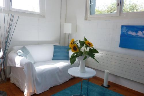 een woonkamer met een witte bank en een tafel met een vaas met bloemen bij B&B Elegant in Ueberstorf