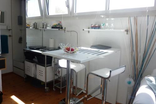 een witte keuken met een aanrecht en krukken. bij B&B Elegant in Ueberstorf