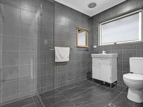 a bathroom with a toilet and a glass shower at Adelaide Holiday Homes in Adelaide