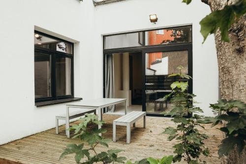 a patio with a bench and a table and windows at La Terrasse des Guillemins by WelcHome in Liège