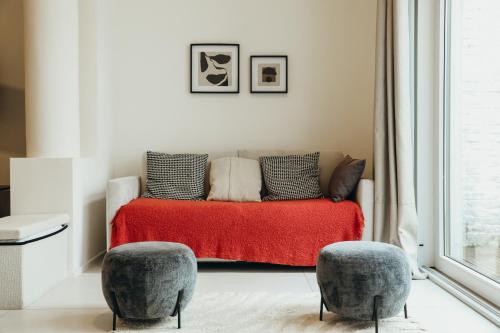 a living room with a couch with a red blanket and two chairs at La Terrasse des Guillemins by WelcHome in Liège